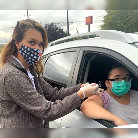 Ashley Seyfarth, PharmD, administers a COVID-19 vaccine to a patient at a drive-through clinic in Bloomfield, New Mexico.