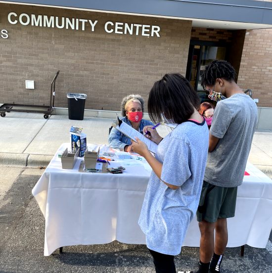Eva Vivian, PharmD, PhD, (wearing red mask) educating a vaccine hesitant youth and parent about the COVID-19 vaccine at the Goodman Community Center in Madison, Wisconsin.