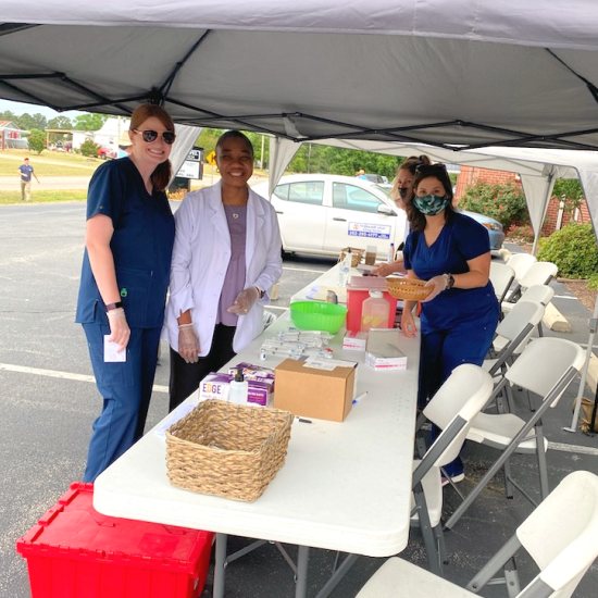 Ijeoma Uwakwe, PharmD, (white coat) and colleagues prepare for a vaccine clinic at Nobles Chapel Baptist Church in North Carolina.