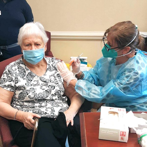 Jill Bebey, PharmD, vaccinates a resident at Carriage Green at Milford, an assisted living facility in Connecticut.