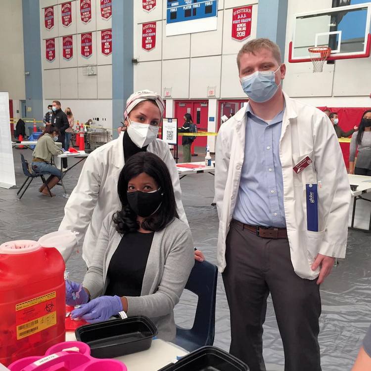Pharmacist Christina Madison (seated) and 2021 PharmD graduates at a COVID-19 vaccination event in a Las Vegas–area high school.