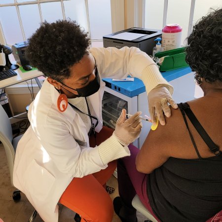 Pharmacist Damika Walker administers a COVID-19 booster shot to a longtime patient at Grubb’s Pharmacy in Capitol Hill.