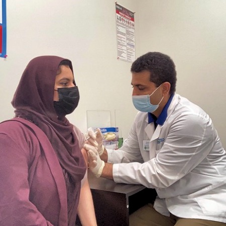 Pharmacist Faheem Rashidi administering a COVID-19 vaccine to a patient at his pharmacy in Lincoln, Nebraska.