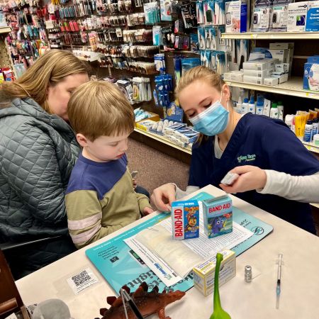 Pharmacist Kristi Riley lets a pediatric patient choose his kiddie-themed bandage before he receives a COVID-19 vaccine at Lebanon Shops Pharmacy in Pittsburgh, Pennsylvania.