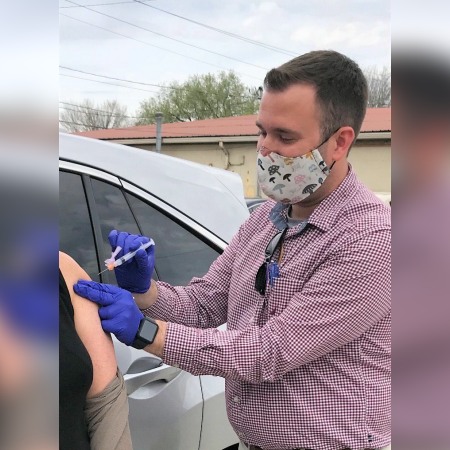 Pharmacist Tyler Duncan administers a COVID-19 vaccine to a patient at her car in the parking area outside Baggett Pharmacy in Kingston, Tennessee.