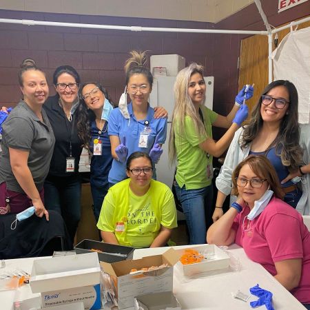 Pharmacists Heeya Ju (center, wearing blue shirt) and Jeanna Szablicki (back row, 2nd from left) along with a team of health care professionals and support staff at a COVID-19 vaccination event in Nogales, Arizona.