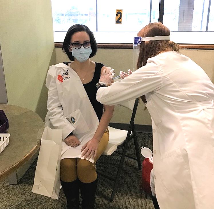 Renee Robinson, PharmD, receives a COVID-19 vaccine from UAA/ISU pharmacy student Talethia Bogart.
